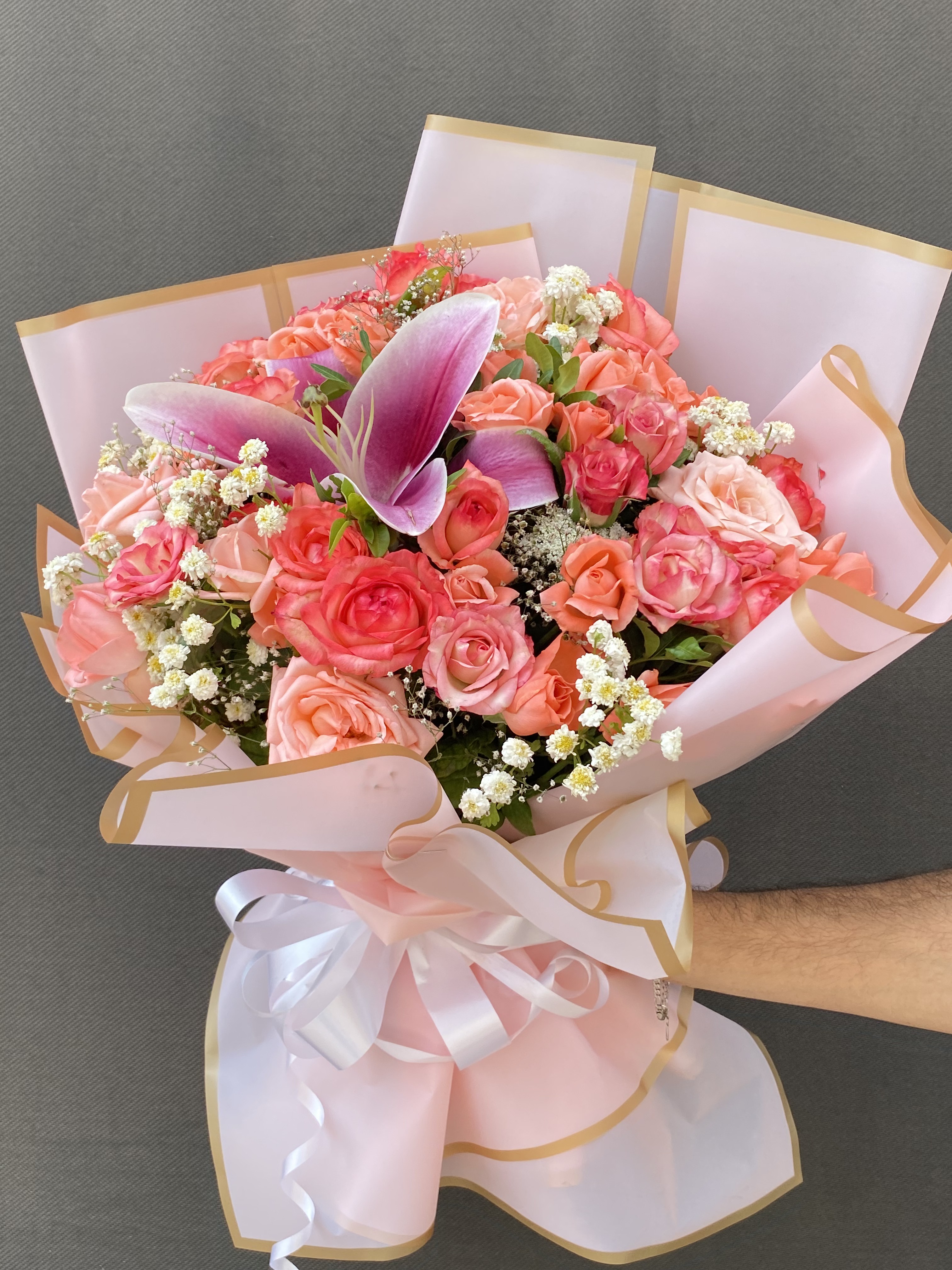 Pink and peach roses with a pink lily and baby's breath in blush wrap, Douce Dévotion bouquet delivery in Fes